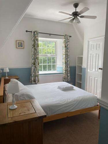 a bedroom with a bed with a ceiling fan and a window at Inn On The Wye in Ross on Wye
