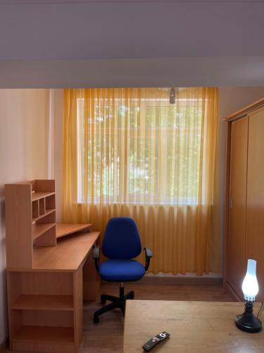 um escritório com uma cadeira azul, uma secretária e uma janela em One Bedroom Apartment Near Buyuk Ipak Yuli Metro Station, Located in Downtown em Tashkent