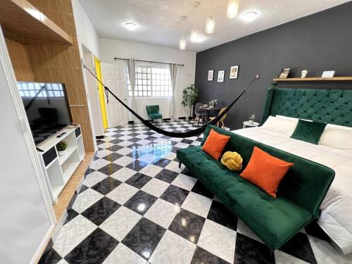 a bedroom with a green couch and a checkered floor at Acogedor y colorido estudio con cama King Size in Mérida