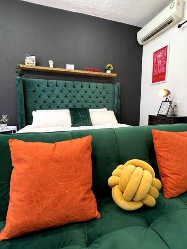 a stuffed animal sitting on a green couch with orange pillows at Acogedor y colorido estudio con cama King Size in Mérida