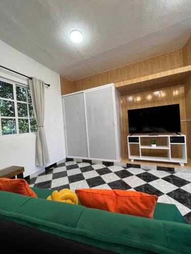 a living room with a couch and a flat screen tv at Acogedor y colorido estudio con cama King Size in Mérida