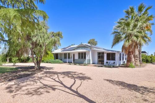 a white house with palm trees in front of it at Kings Billabong Haven in Irymple