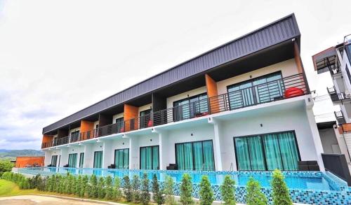 a building with a swimming pool in front of it at Belong Jin The Dam Hotel And Resort in Ban Pha Saeng Lang