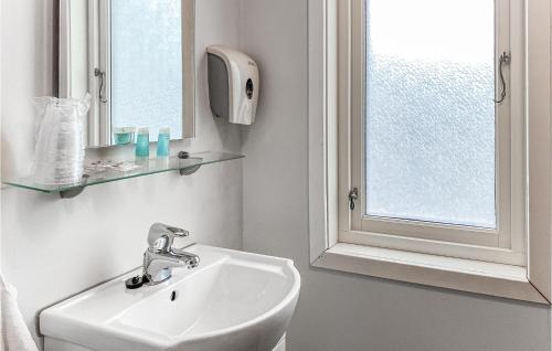 La salle de bains blanche est pourvue d'un lavabo et d'une fenêtre. dans l'établissement Beautiful Home In Offersy With House A Panoramic View, à Offersøy