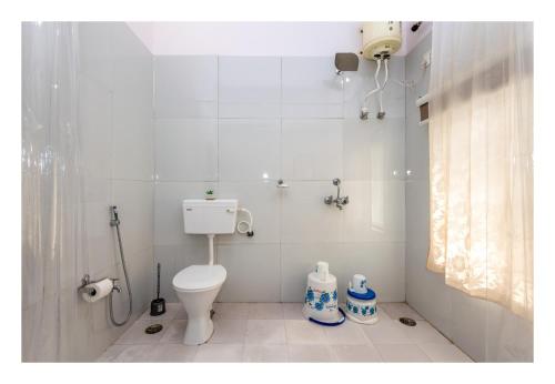 y baño blanco con aseo y ducha. en Tranquility homestay, en Shivpurī