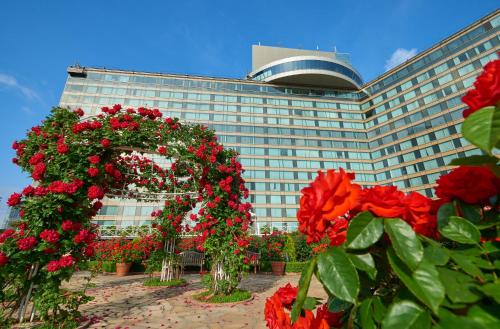 a large building with red flowers in front of it at Hotel New Otani Tokyo The Main in Tokyo