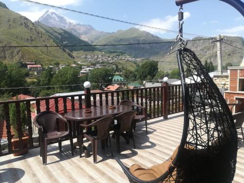 a hammock on a deck with a table and chairs at Come & Rest in Stepantsminda