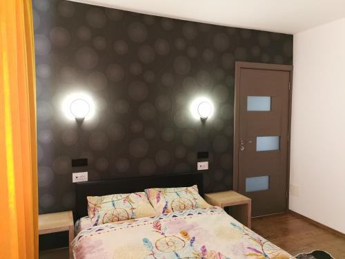 a bedroom with a bed with two lights on the wall at Apartament ASR in Piatra Neamţ
