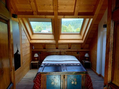 an attic room with a bed and two windows at AL SOGNO in Asiago