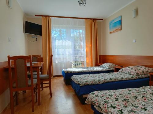 a hotel room with three beds and a table and a desk at Pensjonat Przystań in Kołobrzeg