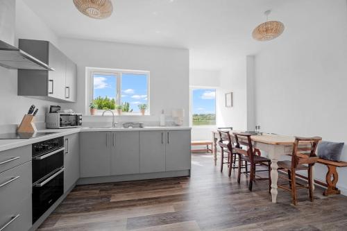 a kitchen with white cabinets and a table with chairs at Bay View Luxury Stays - Southdown in Overcombe