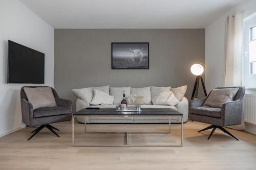 a living room with a couch and two chairs at FACT Apartments in Arnoldstein