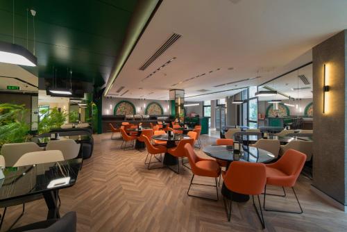 a restaurant with orange chairs and tables in a cafeteria at Dostyk Business Hotel in Aktau