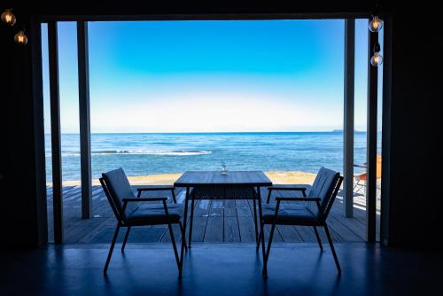 a table and chairs with a view of the ocean at ゲストハウス＆カフェ　ハレテル in Masuda