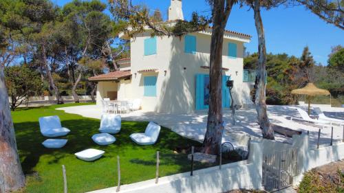 a house with chairs and trees in front of it at Villa Azurella Il Paradiso è qui in Pula