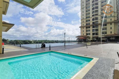 duży niebieski basen obok dużego budynku w obiekcie Kuching Riverine Resort w mieście Kuching