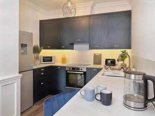 a kitchen with black cabinets and a white counter top at The Yorkshire Hosts - Langton Lodge Apt.9 in Wakefield