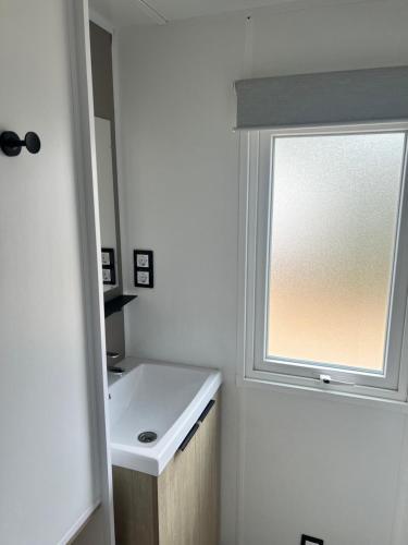 a bathroom with a sink and a window at Mobil home Camping 4* La Falaise Narbonne Plage in Narbonne-Plage