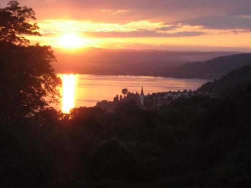 a sunset over a body of water with the sun setting at kleines Landhaus Bodensee in Überlingen