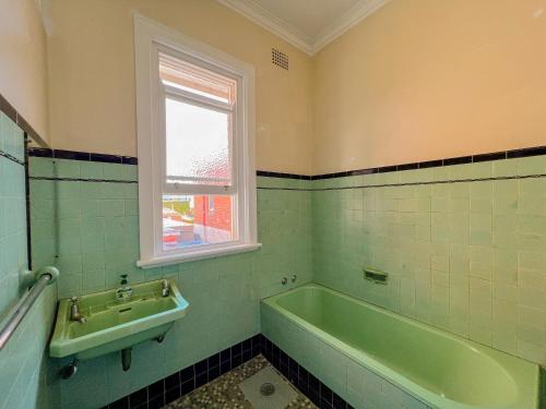 a bathroom with a green tub and a sink at Commercial Hotel Bega in Bega