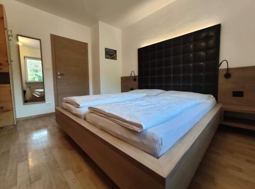 a large bed with a black headboard in a bedroom at Rebleitenhof in Lana