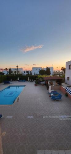 a swimming pool with a sunset in the background at Georgia Apartments in Paphos