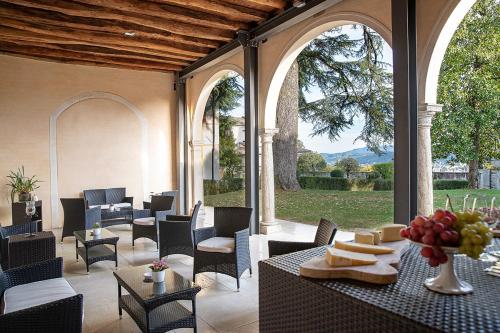 um pátio exterior com mesas, cadeiras e janelas em Villa Premoli - Agriturismo di charme em Cavaso del Tomba