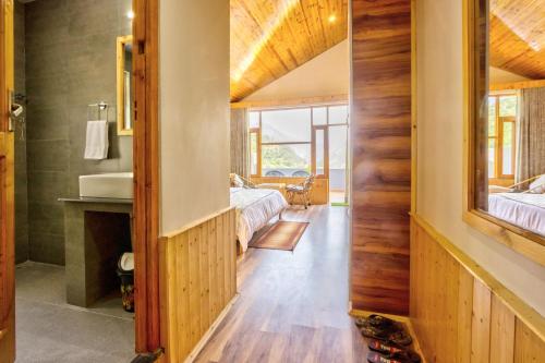a bathroom with a sink and a bedroom with two beds at Doris Mountain Cabins Tirthan in Banjār