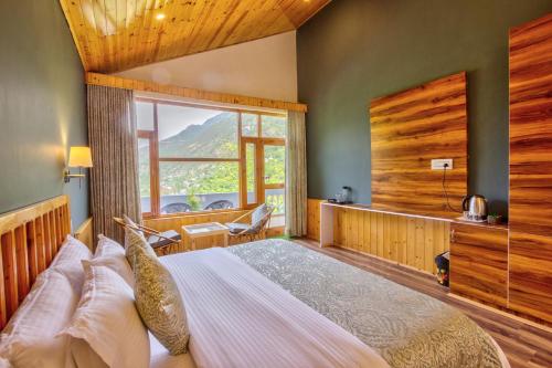 a bedroom with a large bed and a large window at Doris Mountain Cabins Tirthan in Banjār