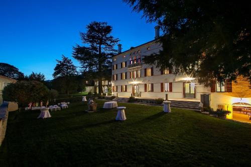 a building with tables in the grass in front of it at Villa Premoli - Agriturismo di charme in Cavaso del Tomba