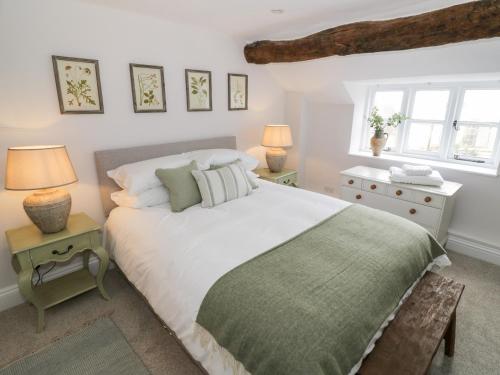 a bedroom with a bed and two lamps and a window at Ashton House in Moreton in Marsh