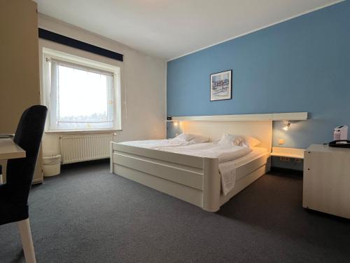 Un dormitorio con una gran cama blanca y una ventana en Hotel Kaufhold - Haus der Handweberei, en Waltrop