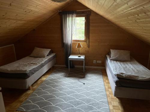 Habitación de madera con 2 camas y ventana en Miekkala Lomatalo en Ilottula