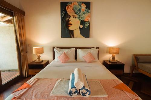 a bedroom with a bed with a painting on the wall at Pera ONE Villas in Gili Trawangan