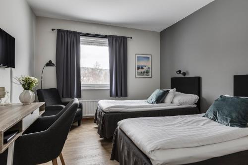 Habitación de hotel con 2 camas, silla y escritorio. en Hotell Kramm en Kramfors