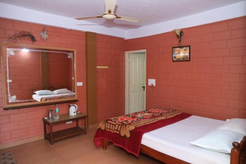 1 dormitorio con pared de ladrillo rojo, cama y espejo en Sai Home Stay en Madikeri