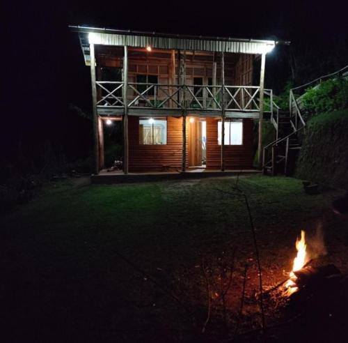 a house at night with a fire in front of it at Noah's Ark Campsite & Restaurant in Fort Portal