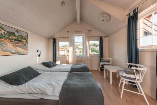 NösundにあるNösund Havshotellのベッドルーム1室(ベッド2台、テーブル、椅子付)