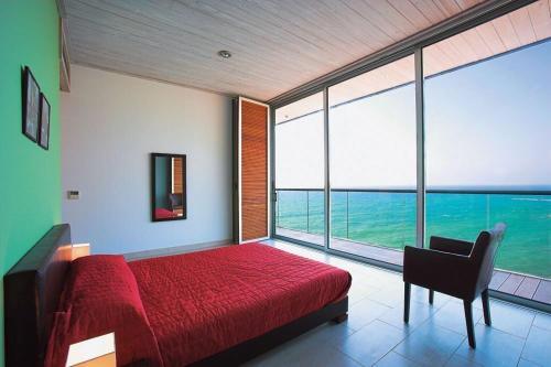 1 dormitorio con cama roja y ventana grande en Villa Aquamarine, en Pomos