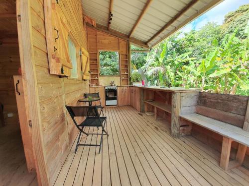 eine Veranda einer Hütte mit einem Tisch und Stühlen in der Unterkunft Le Chalet, Eco Farm Stay in Vieux Grand Port
