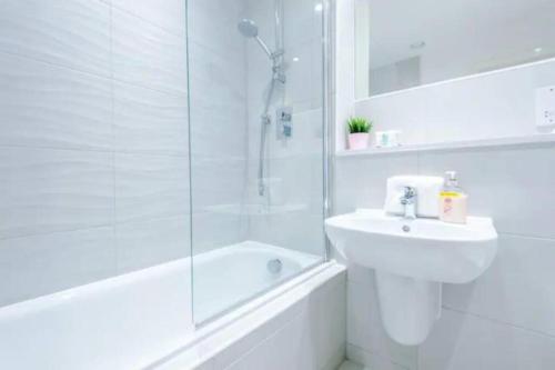a white bathroom with a sink and a shower at Spacious 2-Bedroom Apartment in the Heart of Manchester - Ideal for Families or Groups in Manchester