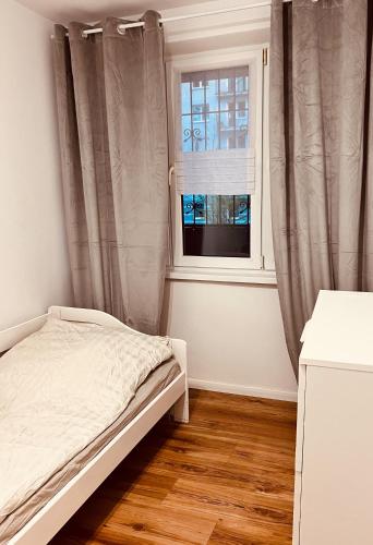 um quarto com uma cama e uma janela em A4 Apartament II em Szczytnica