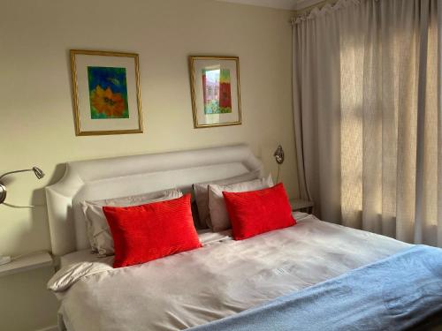 1 dormitorio con 1 cama con 2 almohadas rojas en Secure apartment, 500m from the beach Cathcart Road, Humewood en Summerstrand