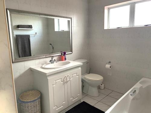 een badkamer met een wastafel, een toilet en een spiegel bij Secure apartment, 500m from the beach Cathcart Road, Humewood in Summerstrand