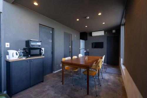 a dining room with a wooden table and chairs at ゲストハウス＆カフェ　ハレテル in Masuda