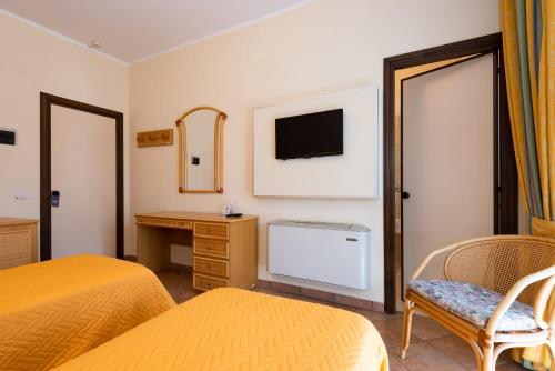 um quarto de hotel com duas camas e uma secretária e uma televisão em Hotel Il Ceppo em Agropoli