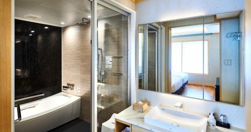 a bathroom with a sink and a tub and a mirror at Enoshima Hotel ーEnoshima Island Spa Hotel Buildingー in Fujisawa