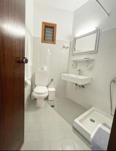 a white bathroom with a toilet and a sink at Pal Beach in Palaiochóra