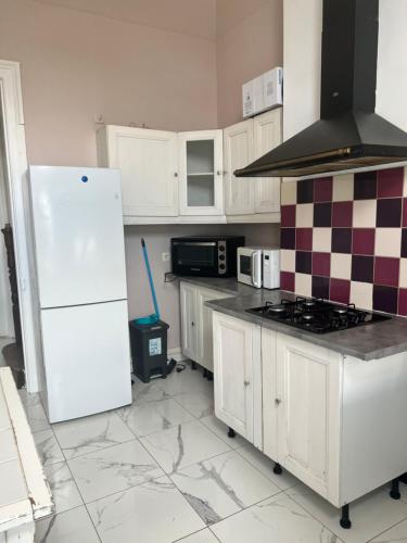 a kitchen with white cabinets and a white refrigerator at Room in Calais