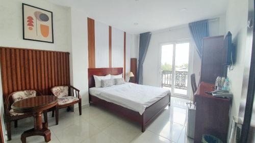 ヴィンロンにあるMinh Khue Hotelのベッドルーム1室(ベッド1台、テーブル、窓付)